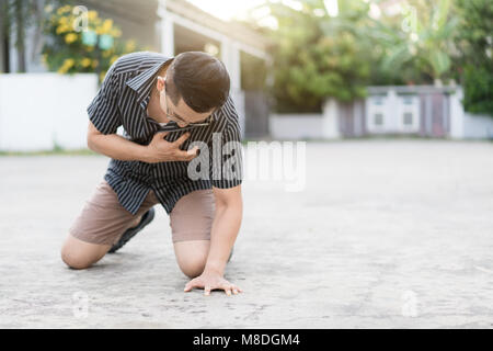 Asian man having heart attack or heart failure at street in home village.  Chest pained seem to be he will get heart attack from disease. Healthcare M Stock Photo