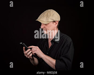 Portrait of a serious person with his smartphone on black background Stock Photo