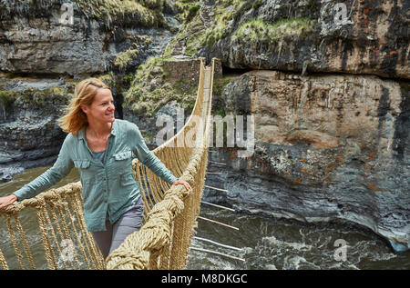 Female tourist crossing Inca rope bridge, Huinchiri, Cusco, Peru Stock Photo