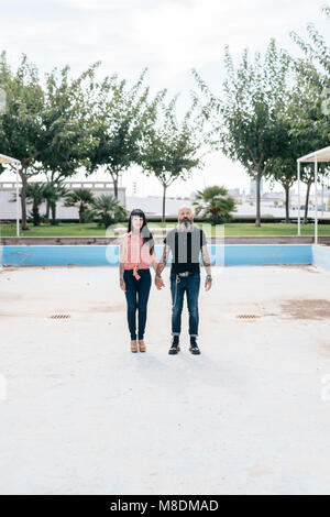 Mature hipster couple standing in empty swimming pool, portrait, Valencia, Spain Stock Photo