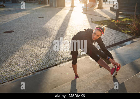 Young woman warming up, stretching legs Stock Photo