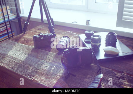 Still life of camera equipment and laptop on table in front of window Stock Photo