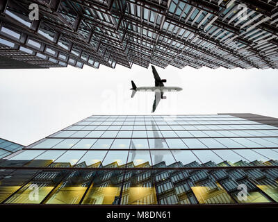 Low angle view of airplane flying  between modern buildings, London City Airport, London, UK Stock Photo