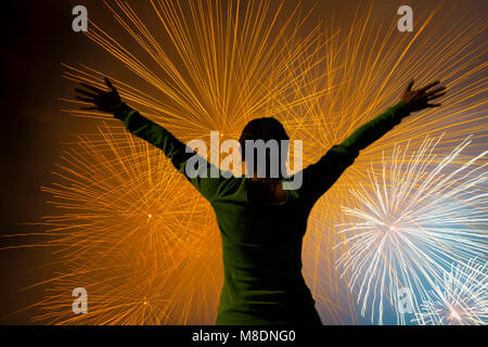 Woman with Arms Outstretched Against Fireworks in Long Exposure in Ticino, Switzerland Stock Photo