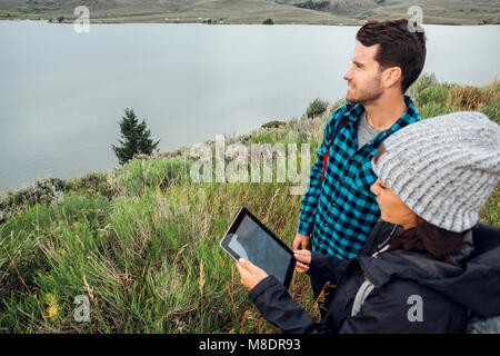 Couple standing beside Dillon Reservoir, using digital tablet, Silverthorne, Colorado, USA Stock Photo