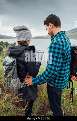 Couple standing beside Dillon Reservoir, using digital tablet, Silverthorne, Colorado, USA Stock Photo