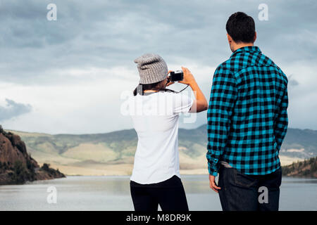Couple beside Dillon Reservoir, taking photograph, rear view, Silverthorne, Colorado, USA Stock Photo