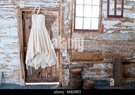 Vintage wedding dress hanging on barn door Stock Photo