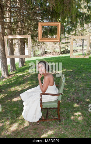 Portrait of bride wearing wedding dress, sitting in chair, outdoors Stock Photo