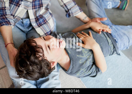 Mother and son at home, son lying on mother's legs Stock Photo