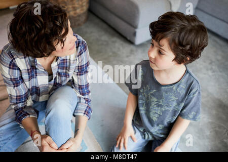 Mother and son at home, sitting on floor, talking Stock Photo
