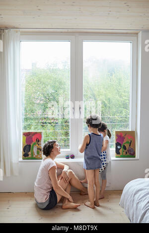 Mother sitting beside window, talking to son and daughter Stock Photo
