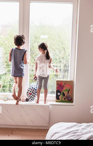 Brother and sister looking out of window, rear view Stock Photo