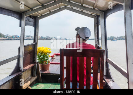 A tourist sits on a chair on one of the many tourist boats on the Meekong Delta, Vietnam Stock Photo