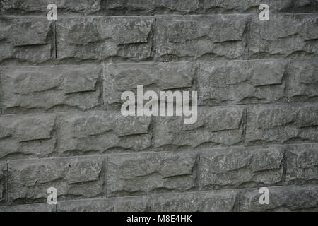 The texture of a stone fence with rectangular blocks and concrete seams. Stock Photo