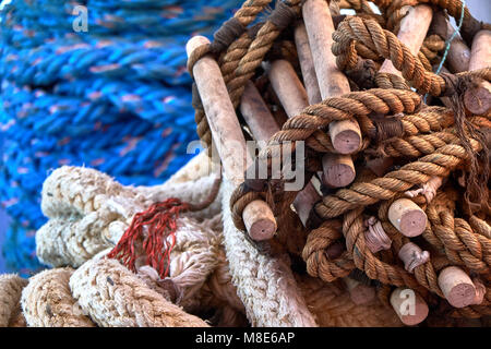 Rope ladder and multicolored ship ropes lie twisted on the blue deck of a passenger ferry closeup view Stock Photo