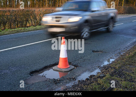 traffic passing large cone marking giant pothole on country road york yorkshire united kingdom Stock Photo