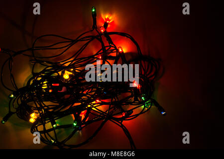 Dark Colorful Christmas background, garland lights on wooden floor with glitter baubles and tinsel Stock Photo