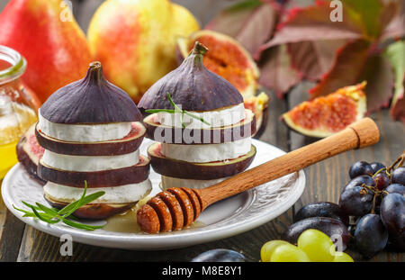 Appetizer of figs and goat cheese with honey. Layered salad of gourmet. Pears, grapes and rosemary on the table. Selective focus Stock Photo