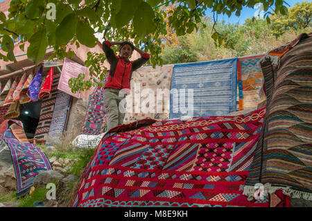 Trekking guide walking among the rugs for sale en route to the Ourika waterfalls in the Atlas mountains, Morocco. Stock Photo