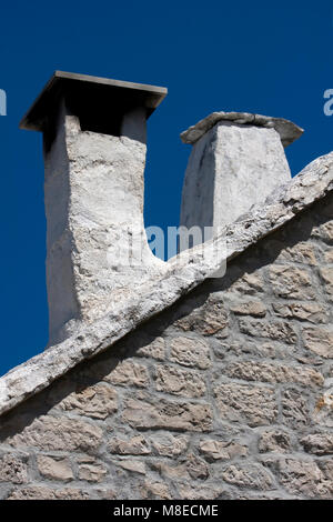 White painted chimneys on old mediterranean stone house in Croatia on island Brac Stock Photo
