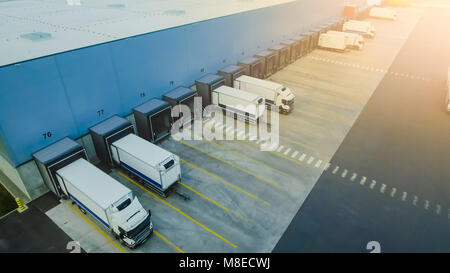 Aerial Side Shot of Industrial Warehouse Loading Dock where Many Truck with Semi Trailers Load/ Unload Merchandise. Stock Photo