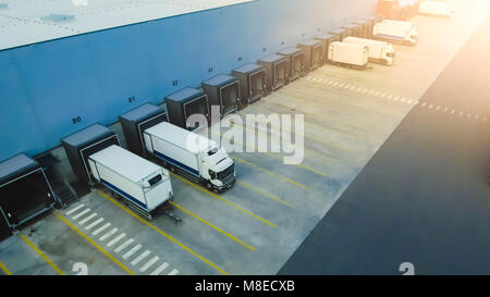 Aerial Side Shot of Industrial Warehouse Loading Dock where Many Truck with Semi Trailers Load/ Unload Merchandise. Stock Photo