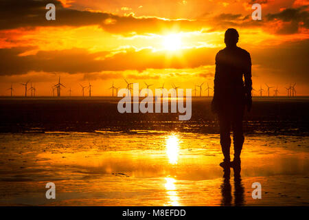 Sunset in Crosby, Merseyside. 16th March 2018. UK Weather.  After a beautiful spring like day of sunshine and blue skies, a stunning sunset silhouettes one of the famous 'Iron Man' sculptures by renowned artist Sir Anthony Gormley on Crosby beach in Merseyside.  Credit: Cernan Elias/Alamy Live News Stock Photo