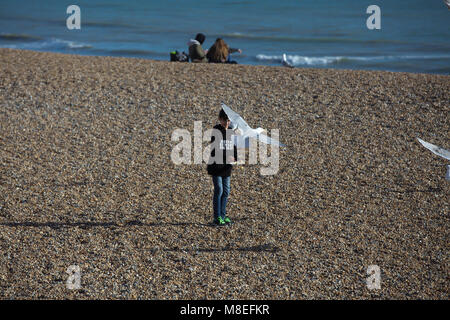 Brighton,UK,16th March 2018,People enjoy the warm and sunny weather and sit on the beach at Brighton.credit Keith Larby/Alamy Live News Stock Photo