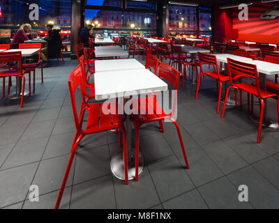 Paris, France - January 5, 2018: Interior of a city fast food restaurant furnished with white tables and red metal chairs. Stock Photo