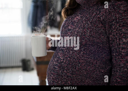 Pregnant woman holding mug with hot beverage Stock Photo