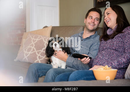 Happy mid adult couple relaxing on sofa with dog Stock Photo