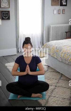 Pregnant woman doing yoga in bedroom Stock Photo