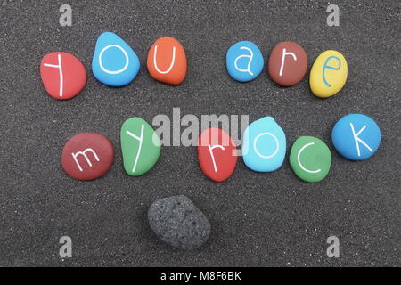 You are my rock, conceptual colored stones composition over black volcanic sand Stock Photo