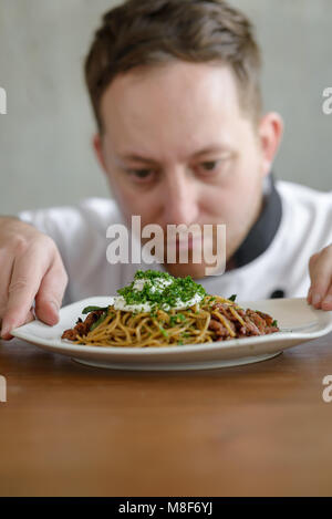 Chef in in a restaurant or hotel kitchen, checking up his food and ready for service to the customer Stock Photo