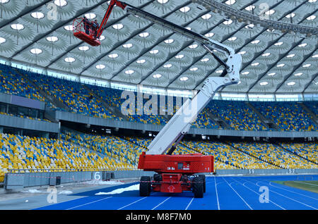 Workers repair sports lighting fixtures of the Olympic National Sports Complex stadium using boom lift. March 16, 2018. Kiev, Ukraine Stock Photo