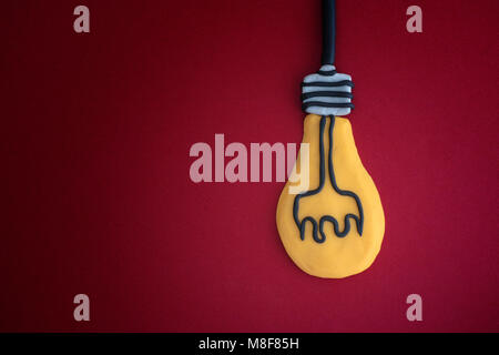 Light bulb made out of play clay on red background. Idea concept. Close up. Stock Photo