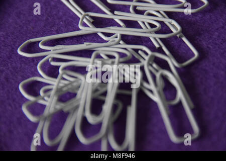 Abstract look of white paperclips on lilac Background Stock Photo