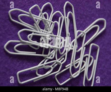 white paperclips on purple felt Stock Photo