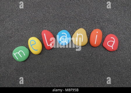 Melania, feminine given name with multicolored painted stones over black volcanic sand Stock Photo