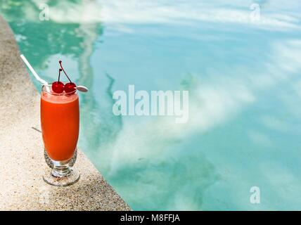 Glass of papaw juice is on edge of pool in the tropical hotel, Maldives Stock Photo