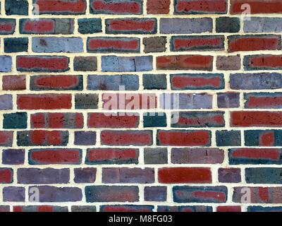 Colorful brick wall background featuring bricks with varying hues of red, green, gray, and blue, with a whimsical water color look Stock Photo
