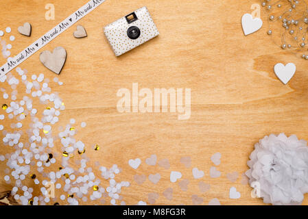Wedding decoration for party with white and gold confetti and wooden hearts lying on wooden background as flatlay Stock Photo