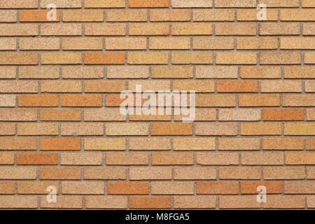 Brick wall background featuring bricks in varying shades of gold and yellow in a traditional running bond pattern Stock Photo