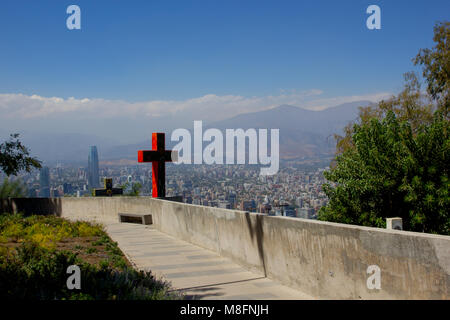 A pathway of crosses on the way to the top of Cerro San Cristobal with a view of Santiago de Chile in the background. Stock Photo