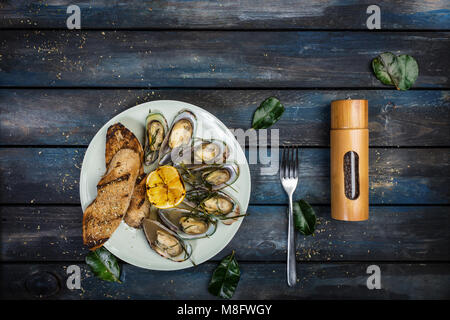 Mussels and bread toasts on on a white plate. Top view Stock Photo