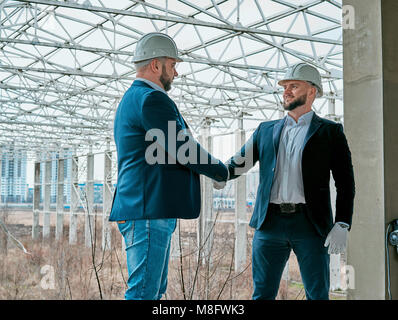 two businessmen shake hands at the construction site Stock Photo