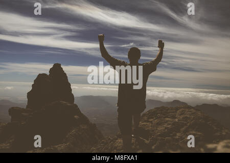 Silhouette man raising up hands on mountain on Gran Canaria island. Stock Photo