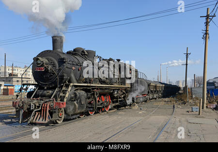 A train of spoil heads through Fuxin towards the tip. The coal mine system at Fuxin, Liaoning province, China, used steam locomotives until mid 2016. Stock Photo