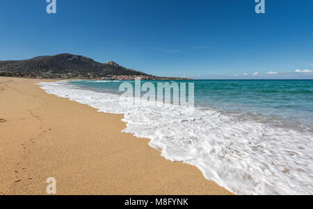 Waves gently washing onto the sandy beach from the  turquoise Mediterranean sea at Algajola in the Balagne region of Corsica under a deep blue sky Stock Photo
